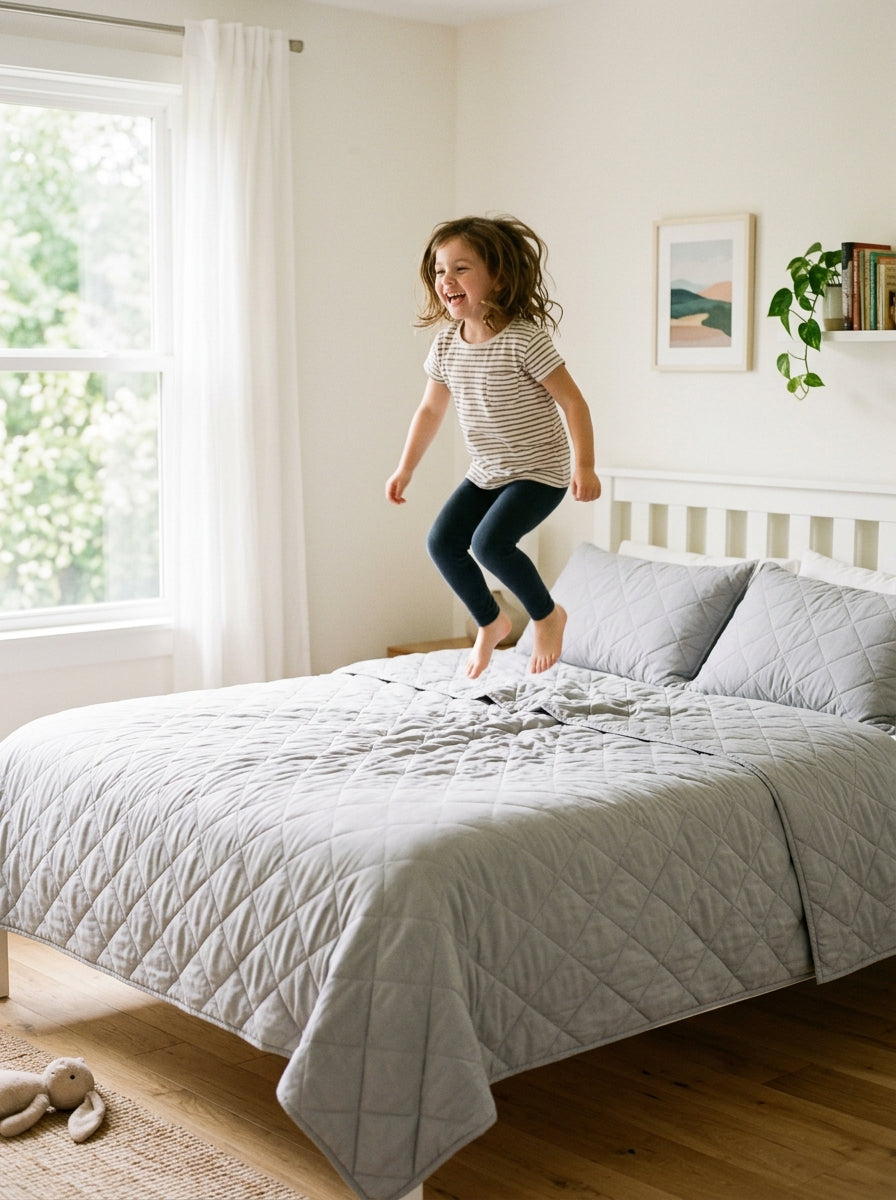 Kind springt auf ein Bett mit DreamWrap in Hellgrau